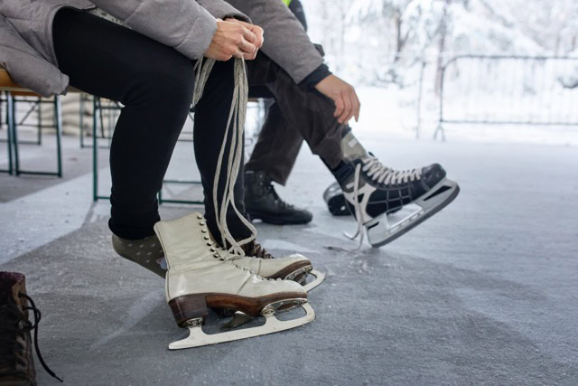 Couple sitting on bench at the ice rink, putting on ice skates